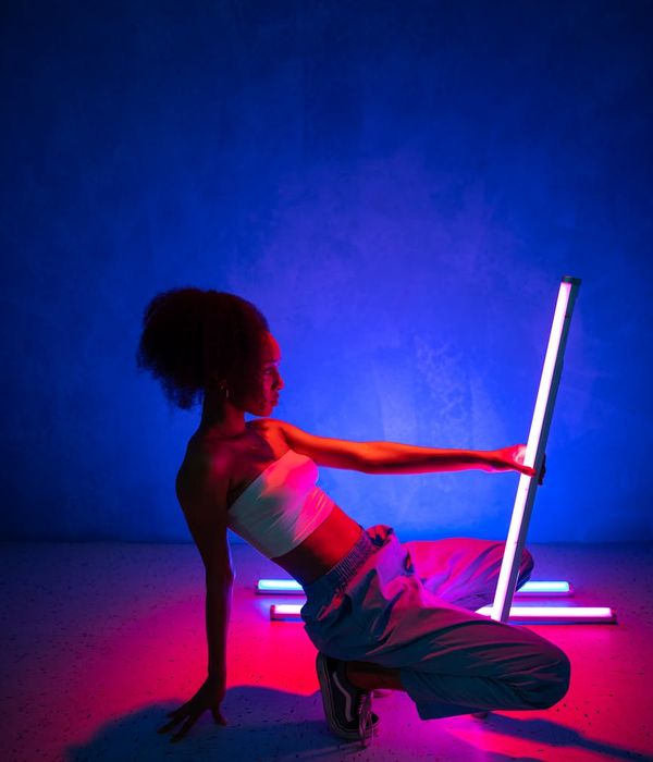 Person in a dynamic cardio pose inside a dark studio with neon green light trails.